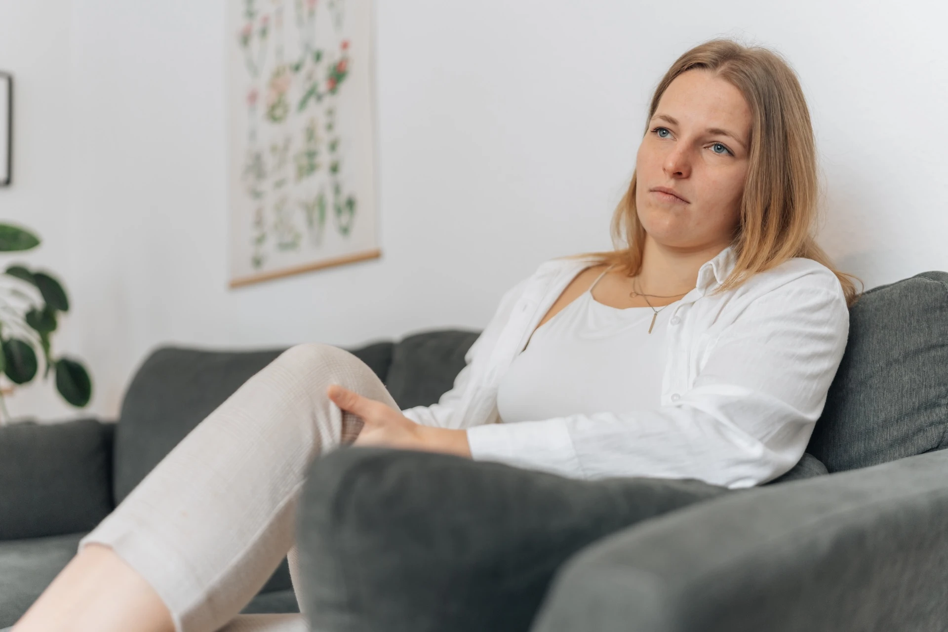 Eine Frau mit Neurodermitis am Bauch sitzt frustriert auf dem Sofa