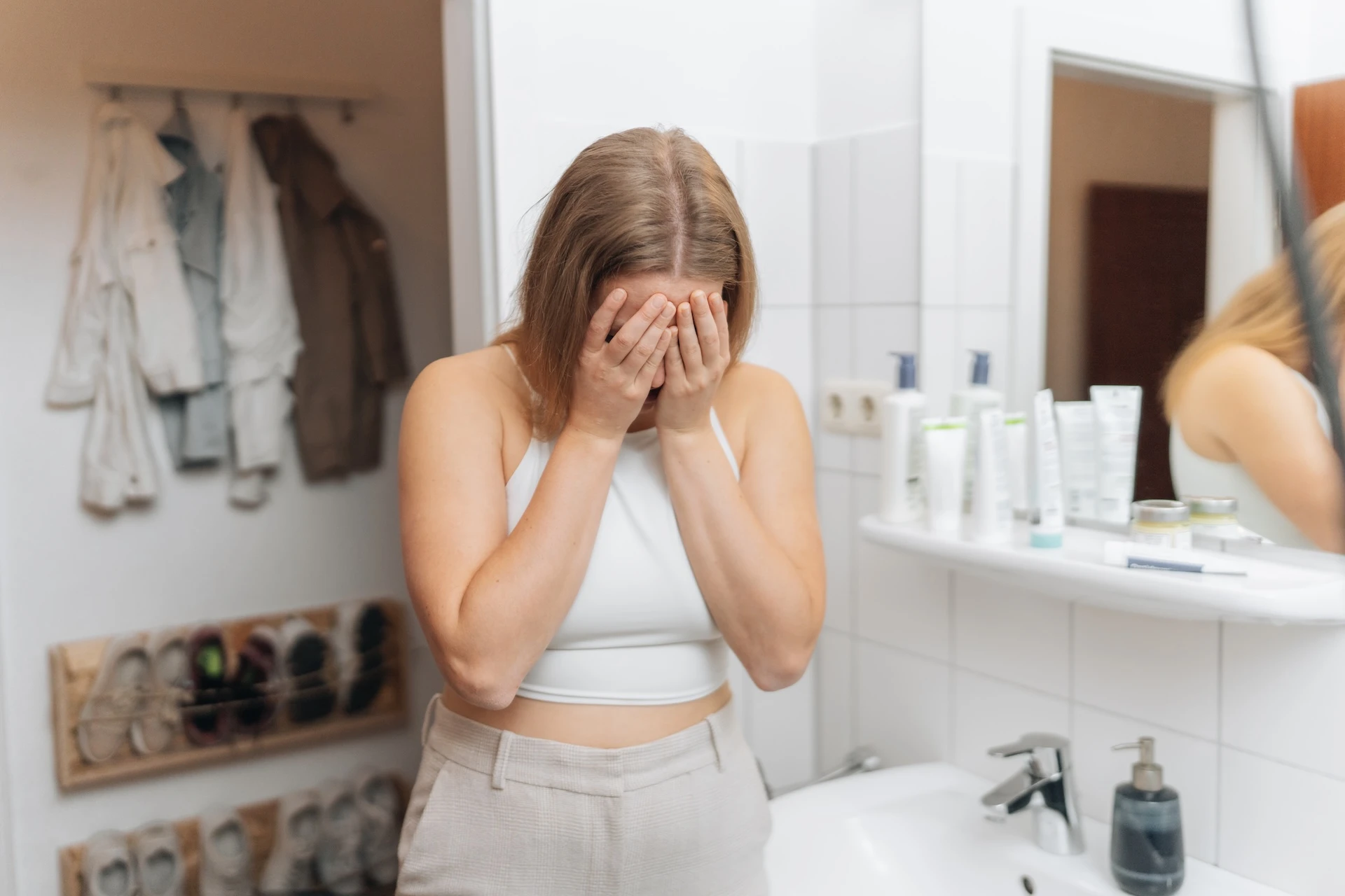 Eine Frau mit Neurodermitis im Intimbereich versteckt sich vor Scham im Badezimmer