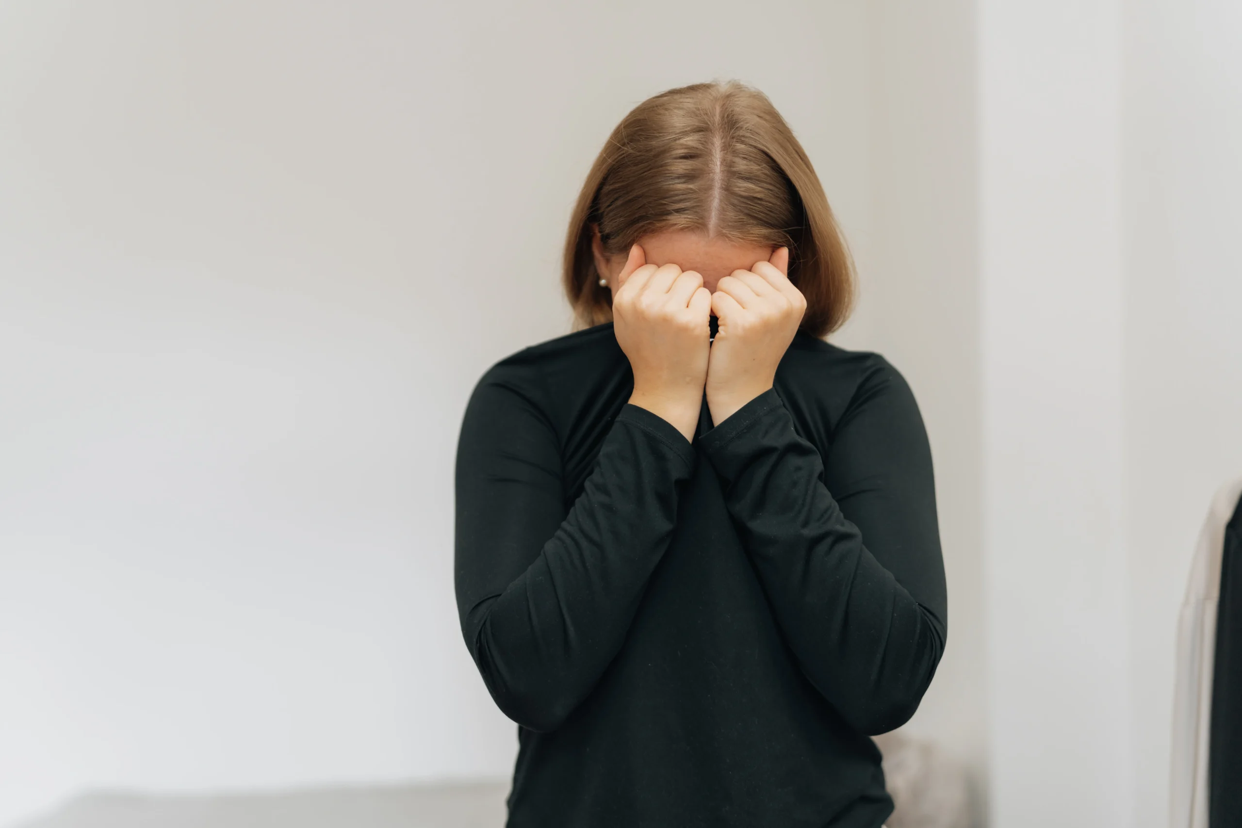 Frau verbirgt ihr Gesicht in den Händen – Ausdruck von Scham und Erschöpfung, wie sie bei Neurodermitis im Intimbereich oft empfunden wird
